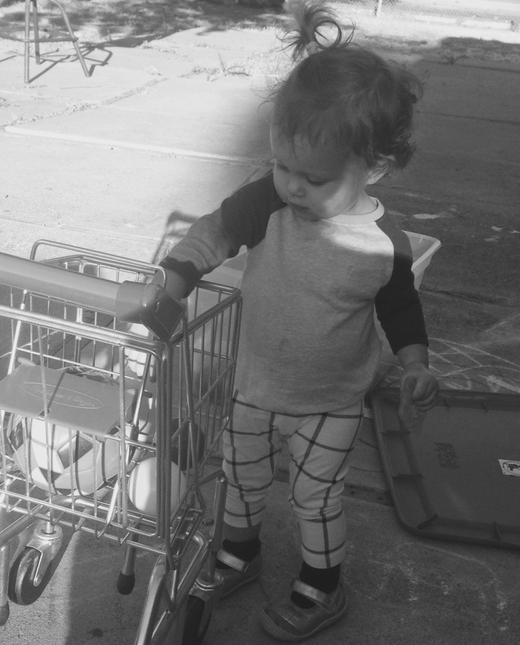 Harlow playing with her own shopping cart in the backyard